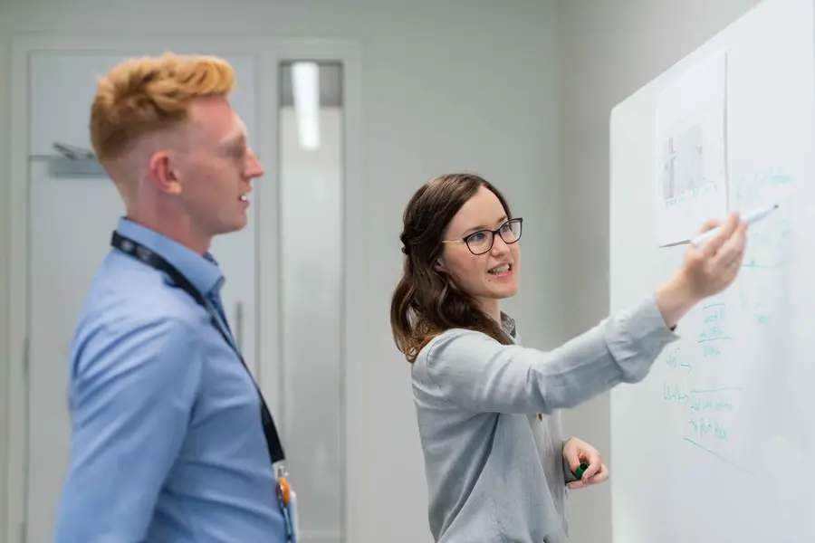 Two colleagues at a whiteboard, as shot