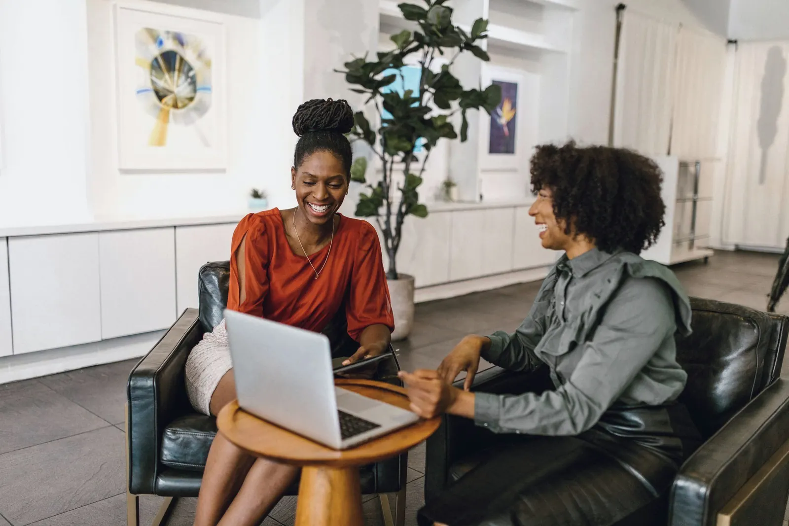 Two colleagues smile as they work through a laptop together.