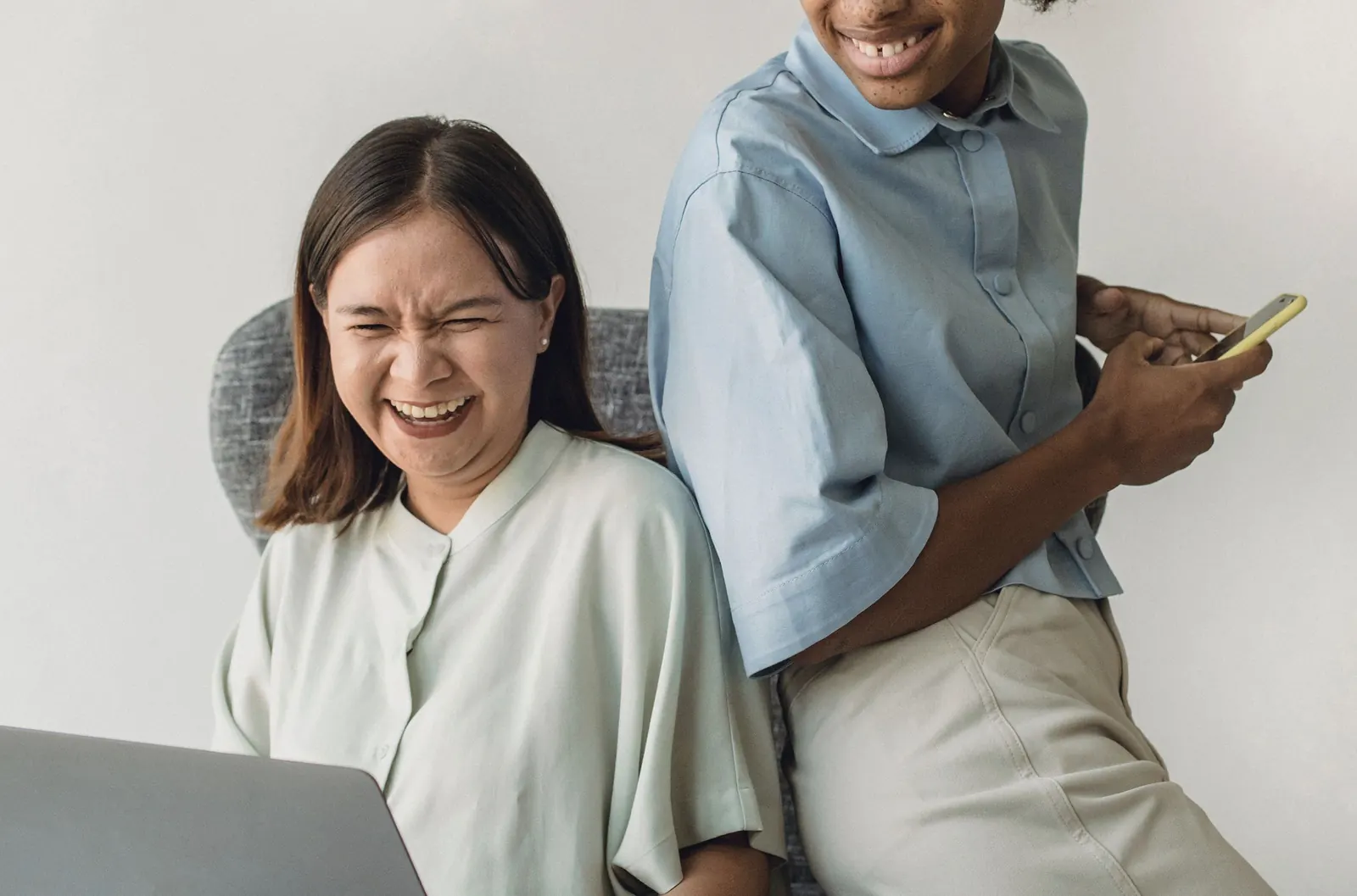 Two colleagues share a laugh over a laptop.
