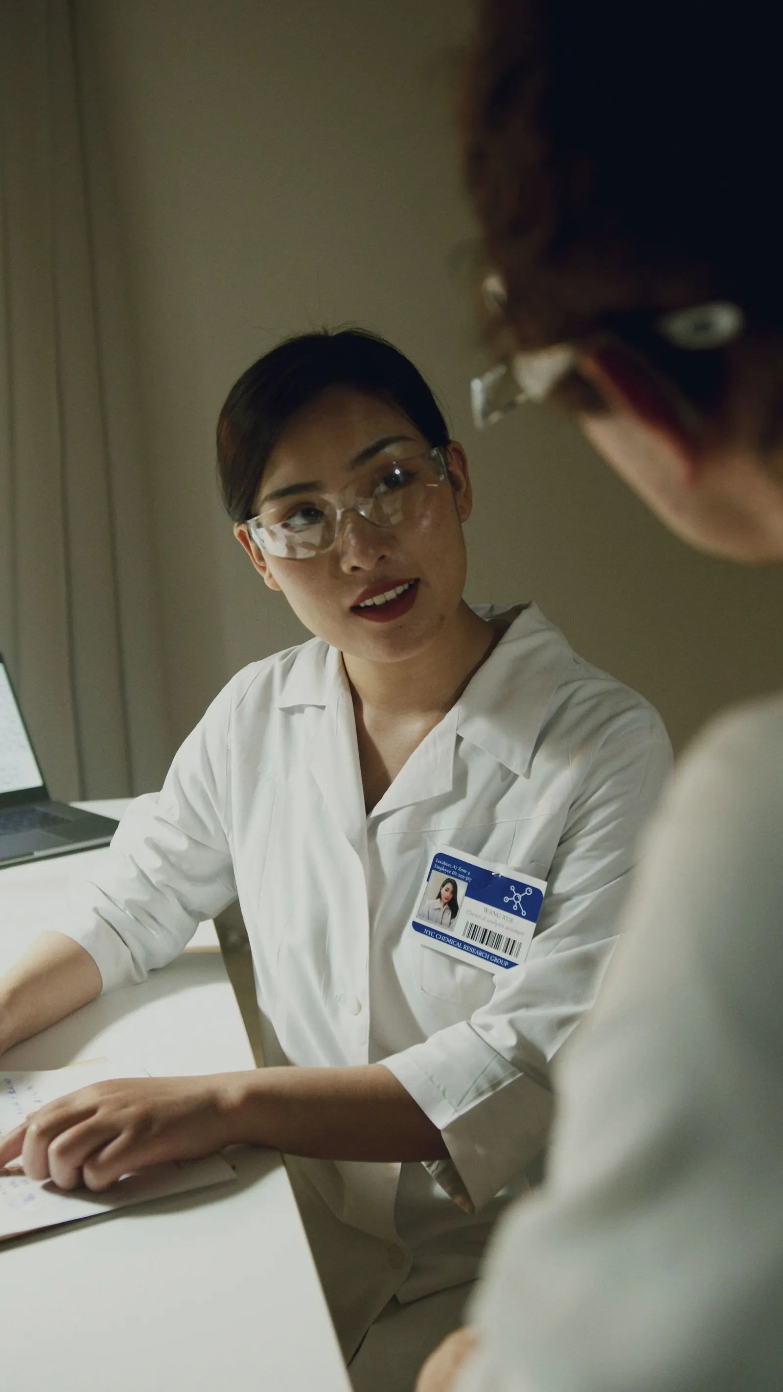A scientist with an ID badge in conversation.