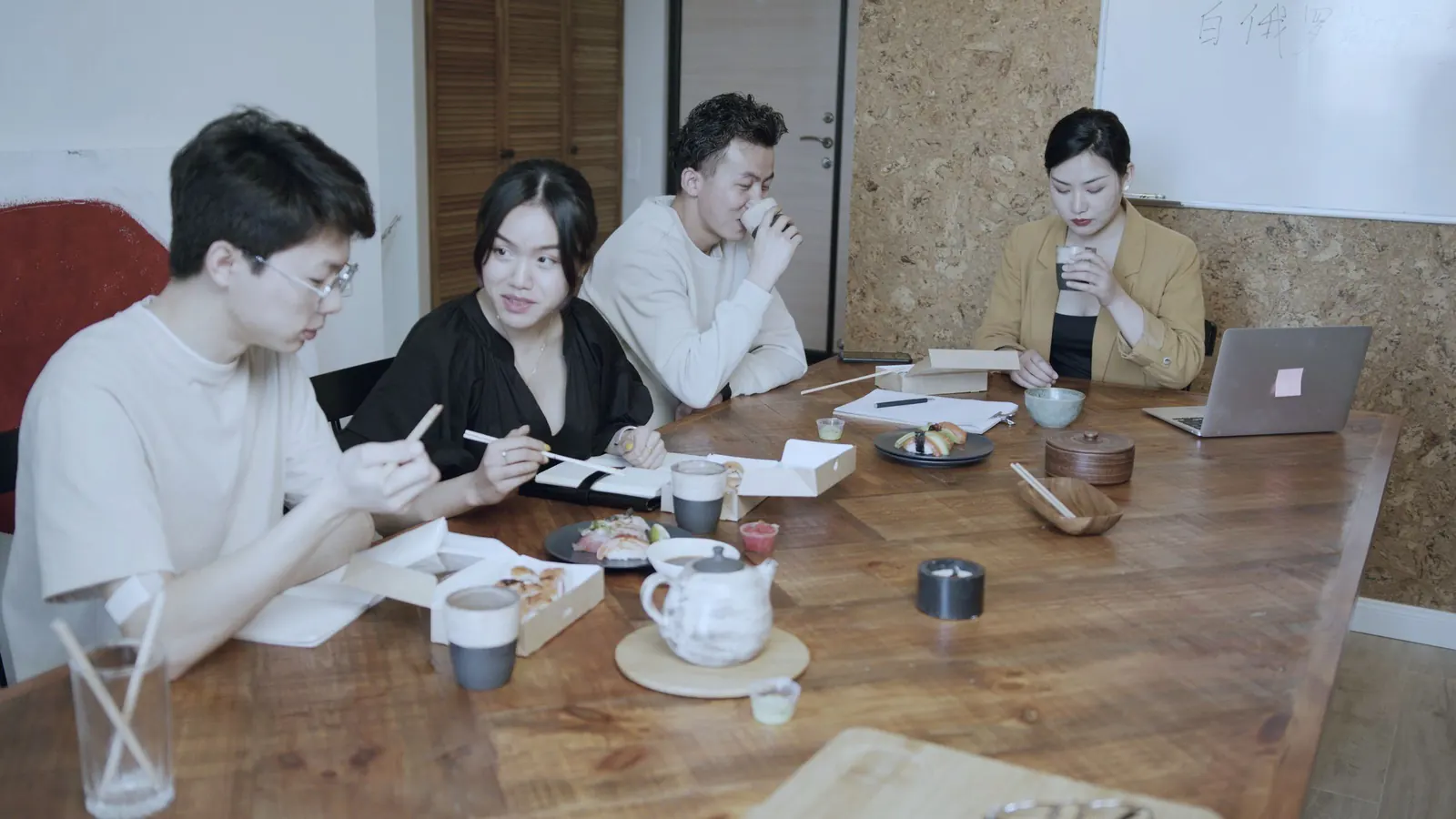A team shares lunch around a wooden table and talks.