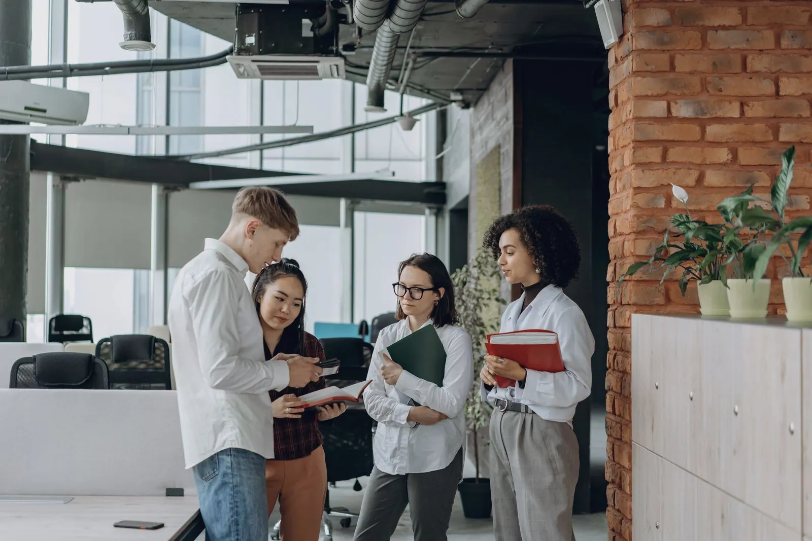 A team stands in a bright office, comparing notes on a plan.