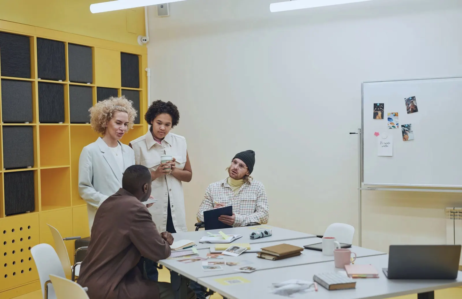 A team talks around a table scattered with notes and sketches.